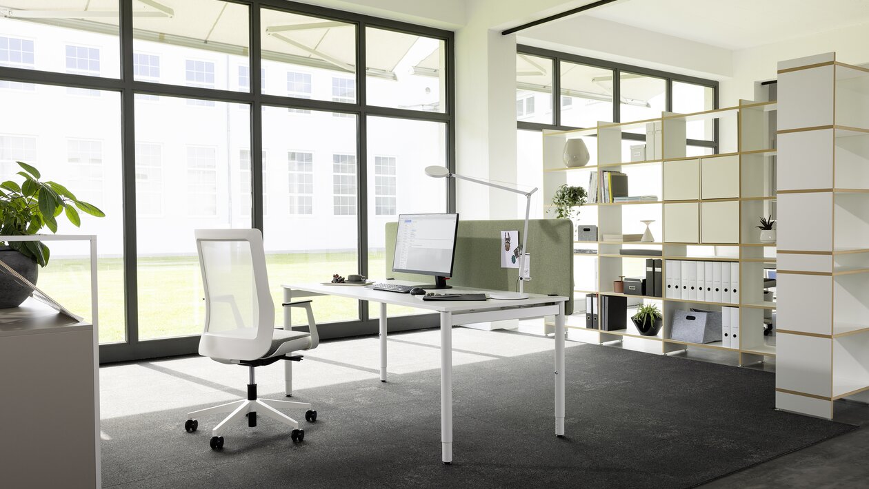 Weißer Schreibtisch mit weißem Drehstuhl in einem hellen Büroraum.