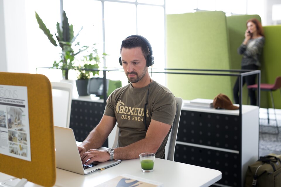 Un homme travaille avec des écouteurs sur son ordinateur portable.