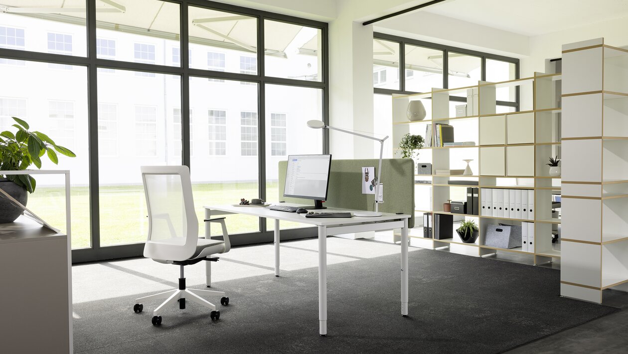 White desk with a white swivel chair in a light office room.