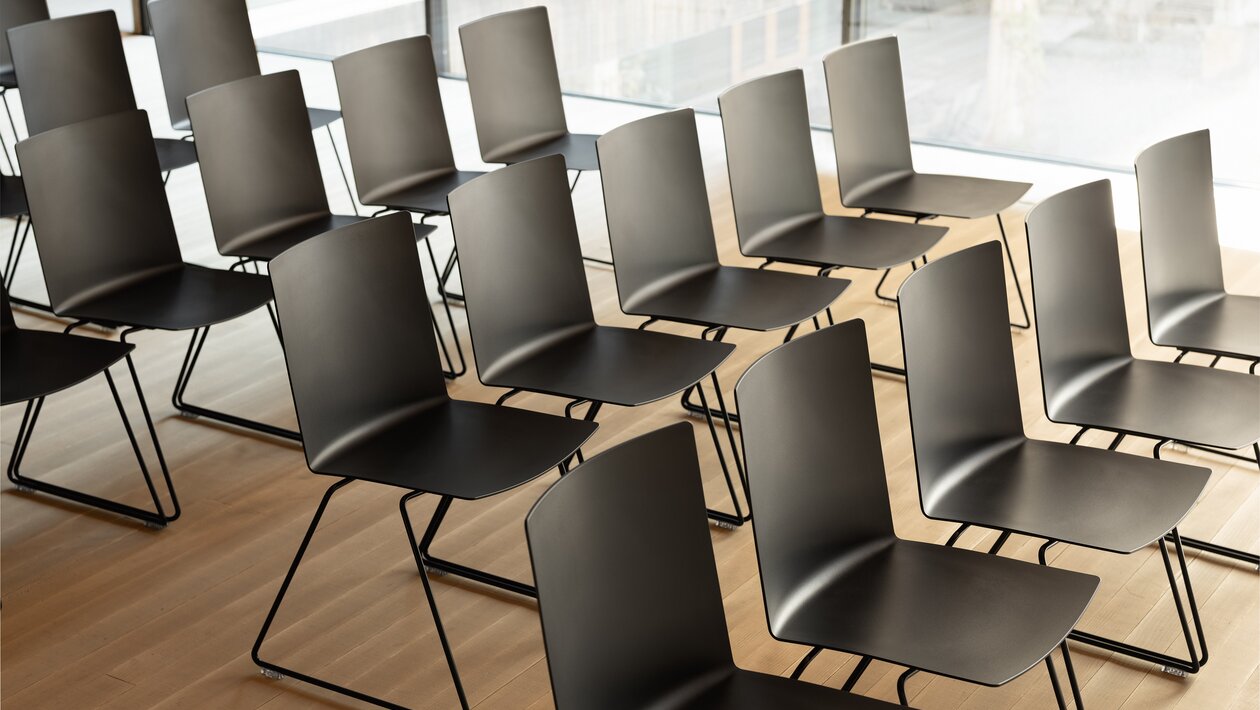 Rangées de chaises noires dans une pièce avec un plancher en bois, vue aérienne