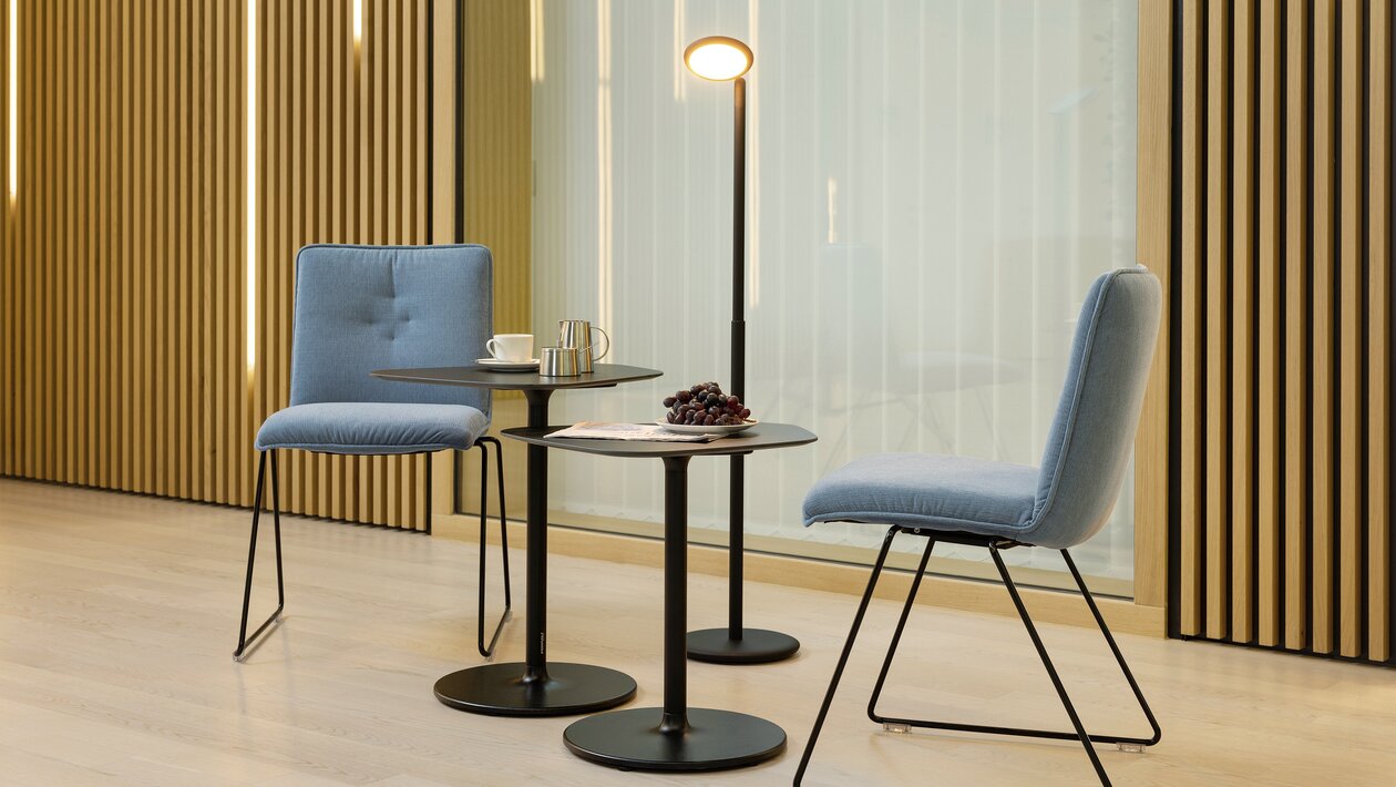 Two blue padded skid-base chairs in front of a wooden wall.