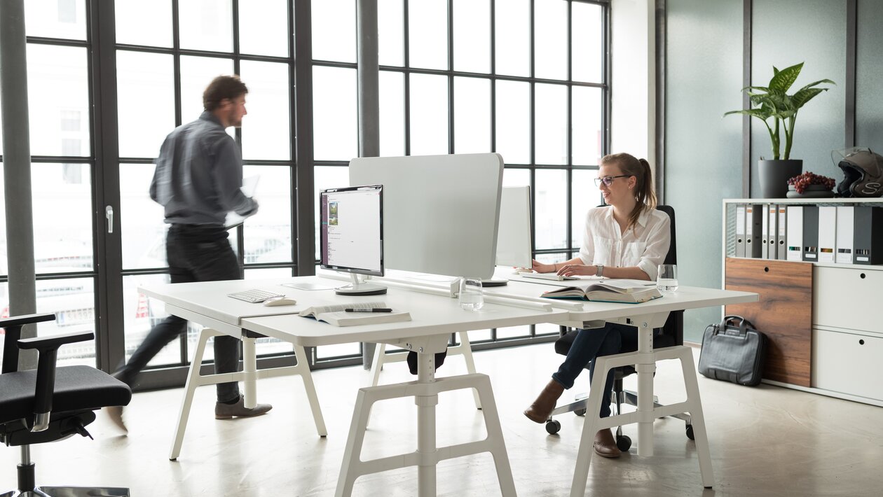 Two people are sitting on an white office desk.
