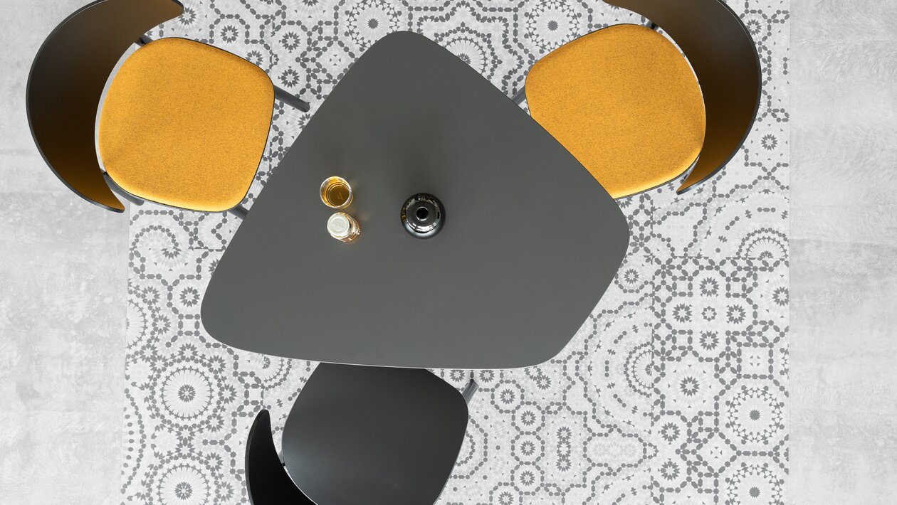 Three wooden chairs at a bistro table, photographed from above.