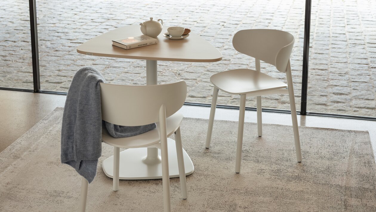 Two light wooden chairs with a bistro table. 