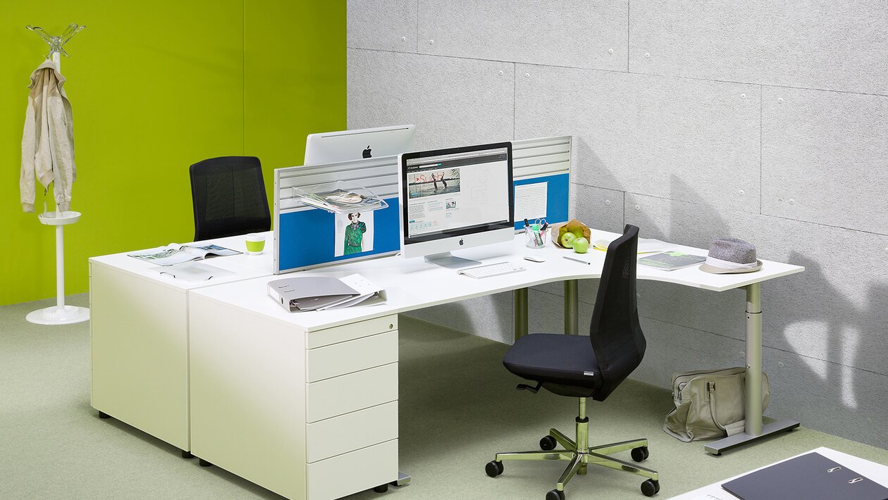 Weißer Bürotisch in einem Raum mit grüner Wand.