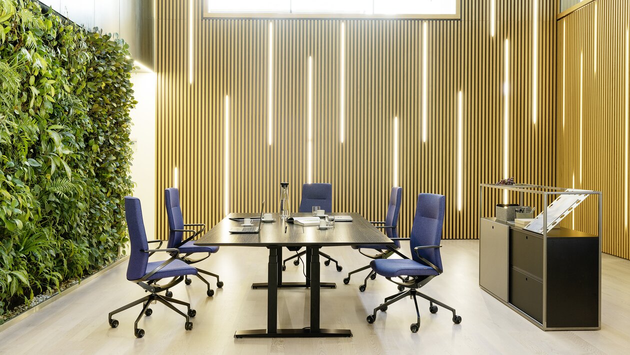 Dunkler Konferenztisch mit violetten Konferenzstühlen. 