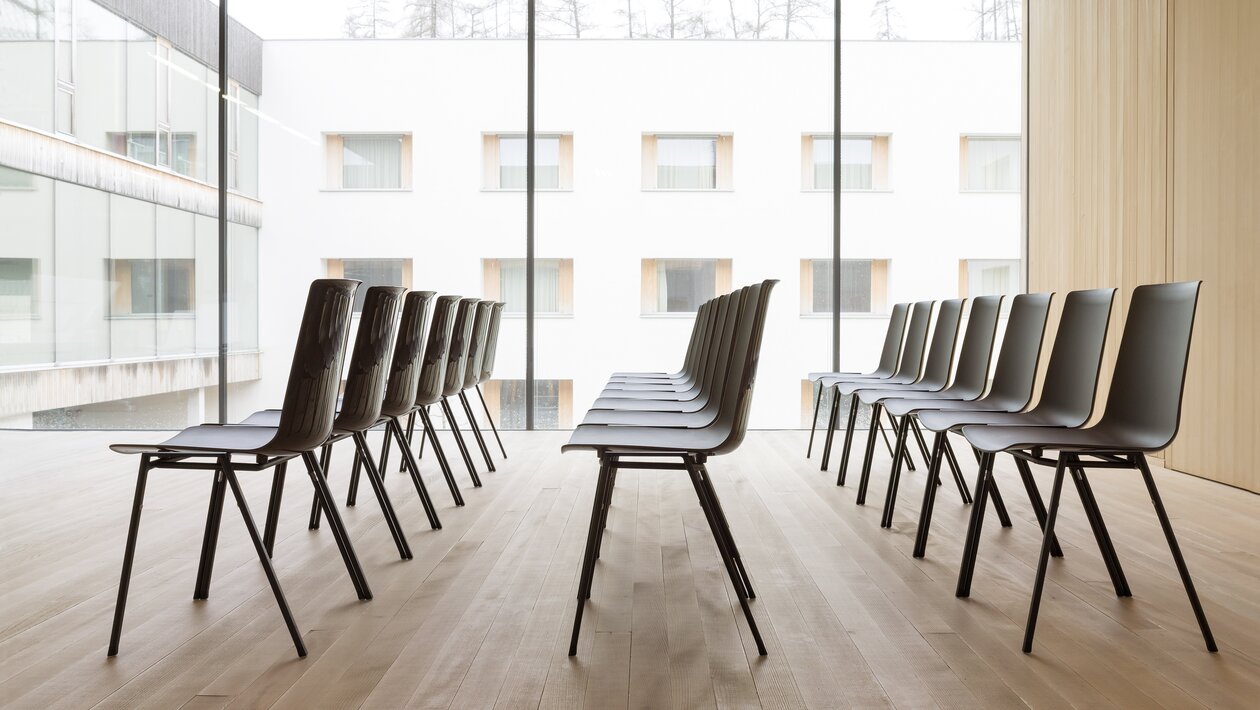 Reihen aus schwarzen Stühlen in einem Raum mit Holzfußboden.