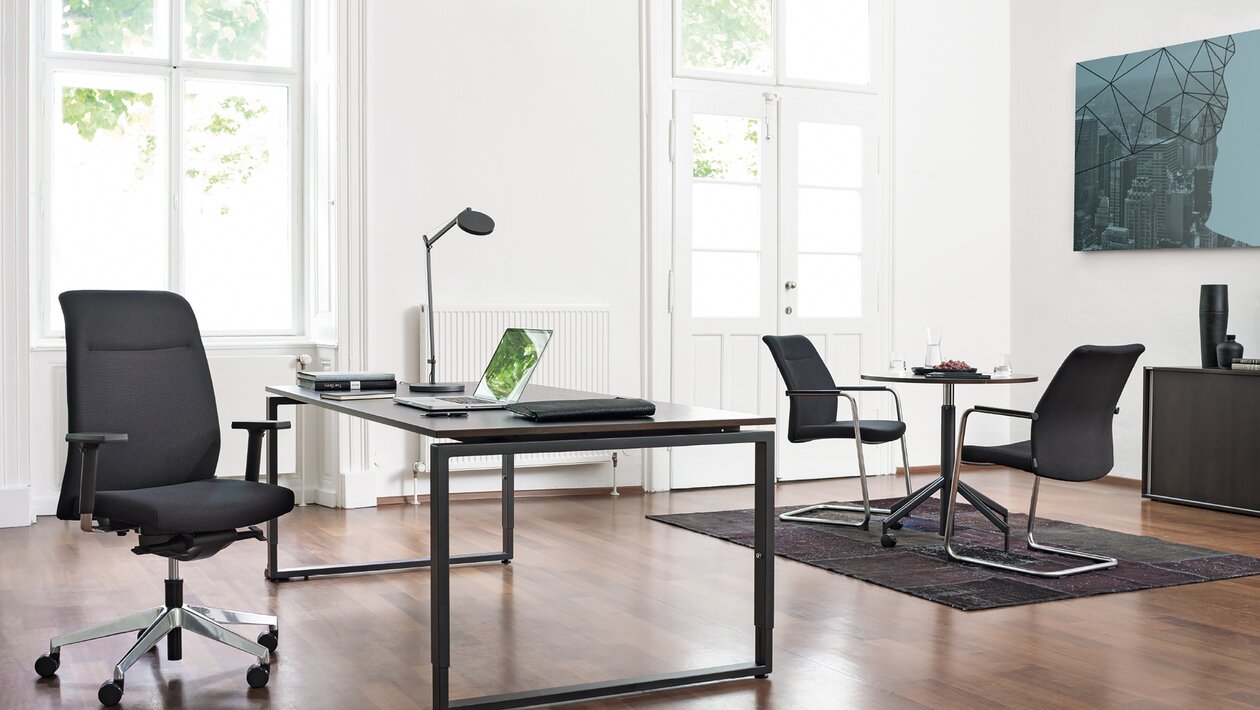 Office with a desk, a black swivel chair and two cantilever chairs.