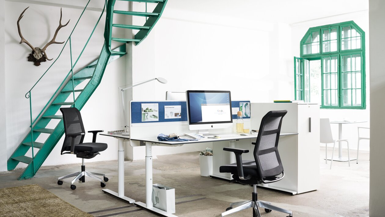 Office with two desks, black swivel chairs and a white cabinet. 