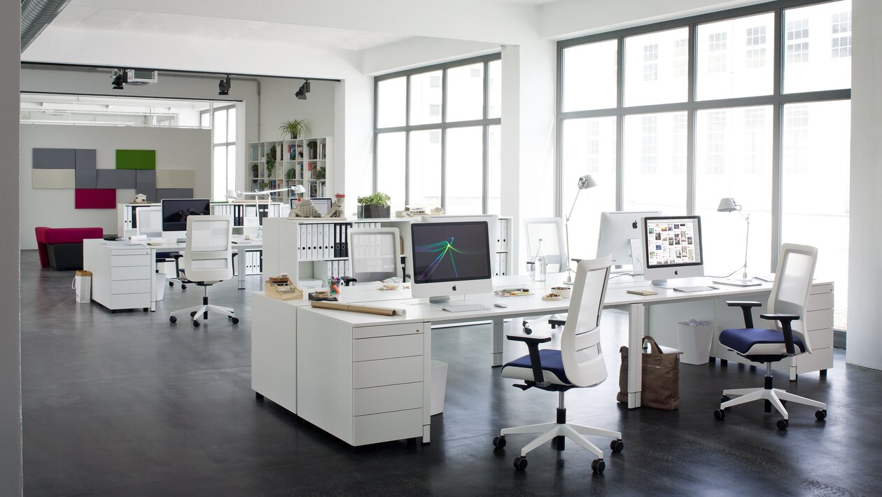 White swivel chairs with white office desks in a modern office.
