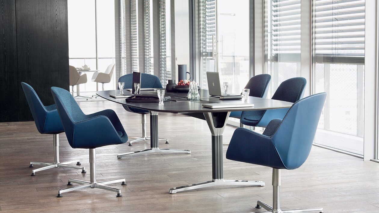 Konferenztisch mit blauen Konferenzstühlen.