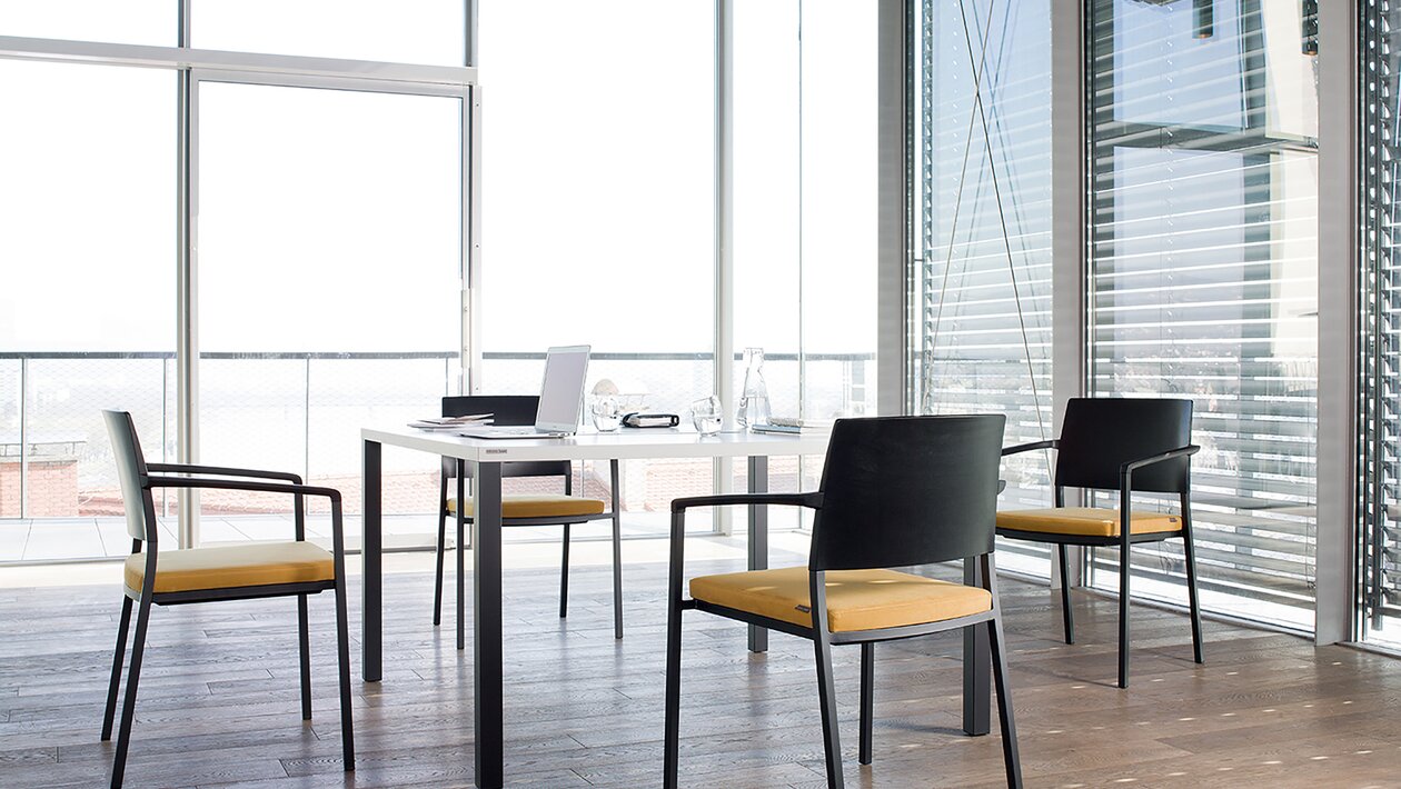 Black chairs with a yellow padded seat at a black table.