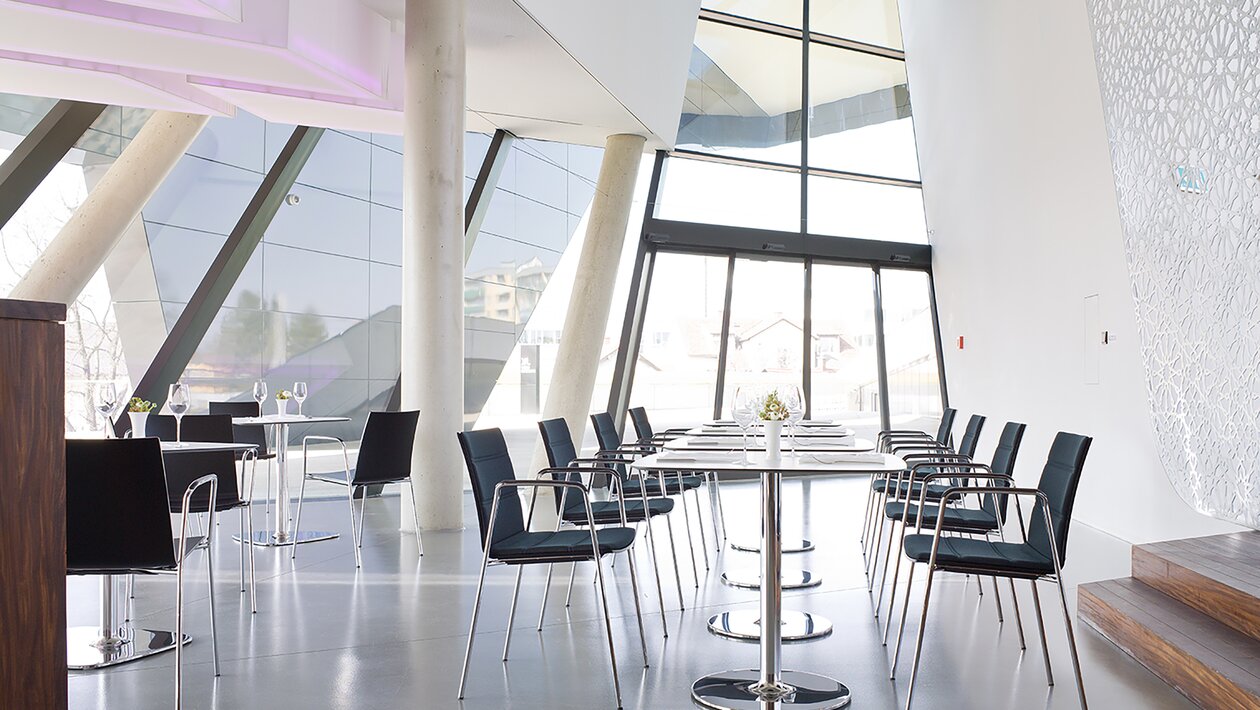 Black chairs with armrest at white bistro tables.