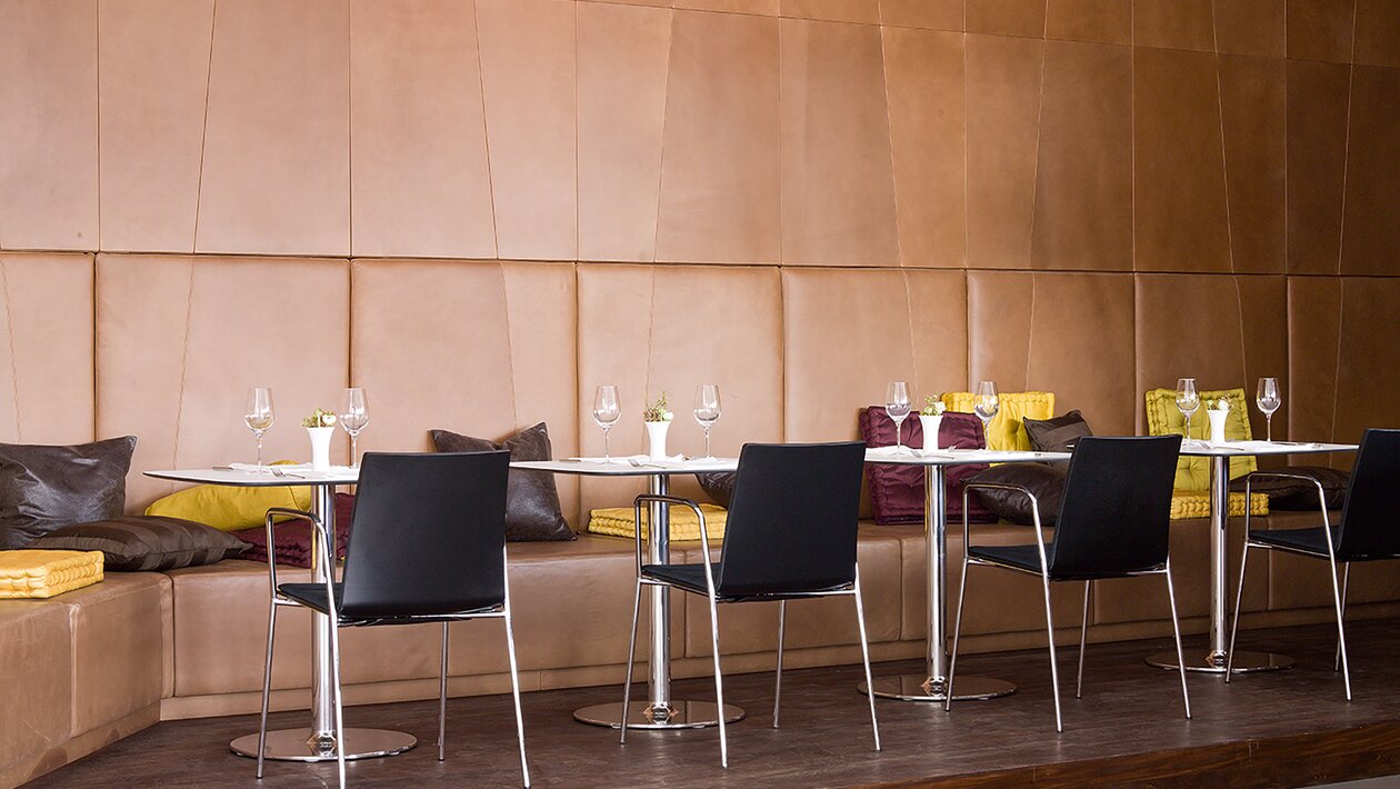 chaises bistro noires et tables bistro blanches devant un mur en cuir