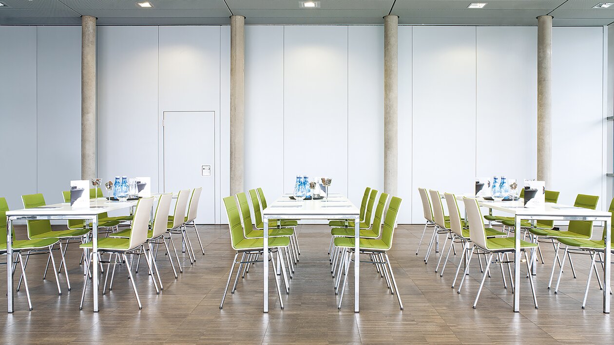 bedrijfsrestaurant met tafels en groen gestoffeerde stoelen