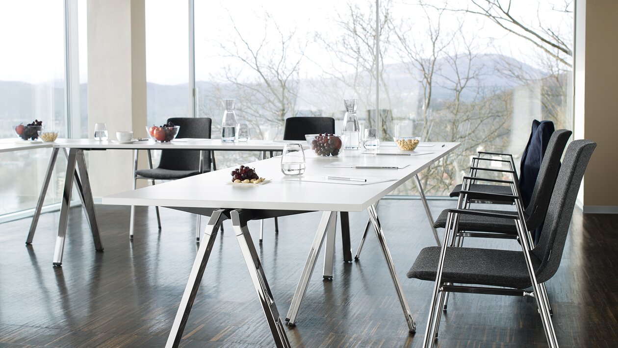 U-vormige vergaderopstelling met rechthoekige tafels en stoelen met grijze stoffering