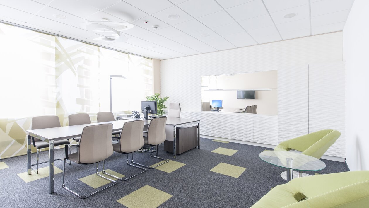 Meeting room with tables, cantilever chairs and a computer.