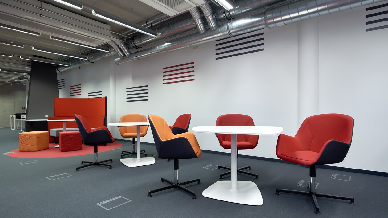 Red and orange lounge seating with white bistro tables. | © raumpixel.at