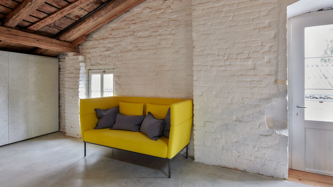 Yellow couch at a white wall. | © raumpixel.at