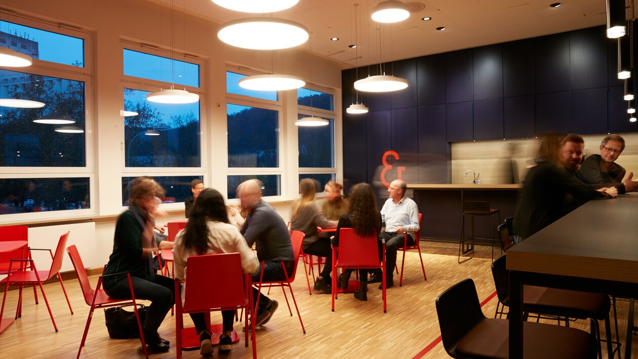 Pratende mensen die zitten op rode bistrostoelen | © Peter Becker GmbH