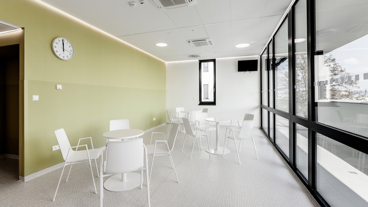 Café-Bereich mit grüner Wand und weißen Möbeln.
