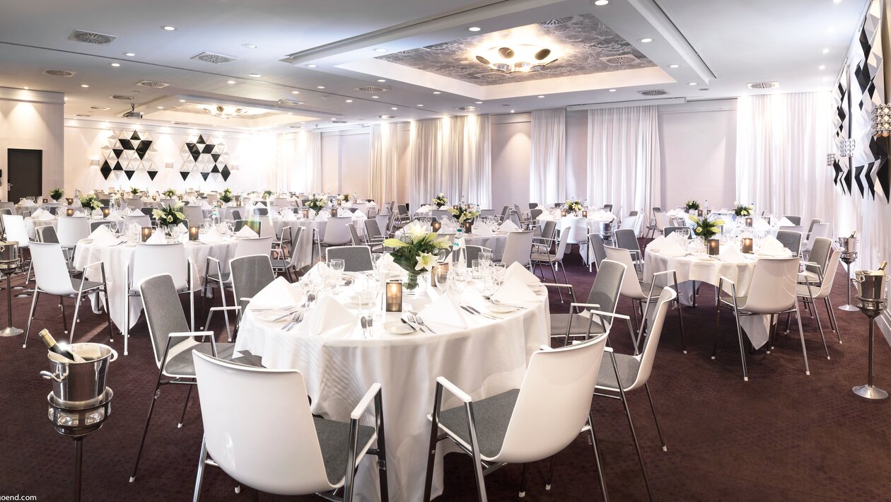 Salle à manger décorée avec tables rondes et chaises blanches. | © studio-bergoend.com