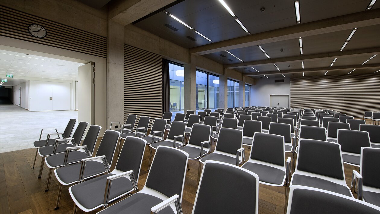 Intégration détaillée d’une rangée de chaises alignées noir et blanc sur un sol en bois.  | © Pichler Fotografen, Urs Pichler