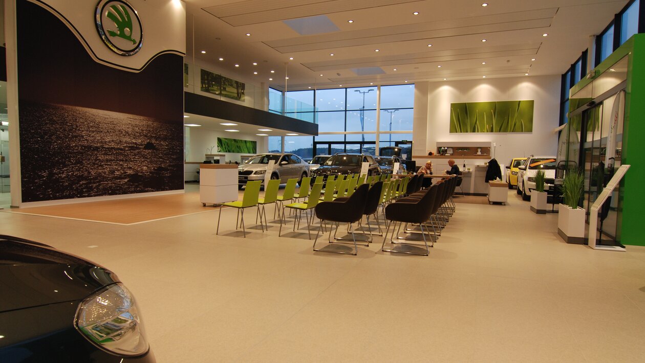 Rijen met groene en bruine stoelen in een Skoda-showroom.