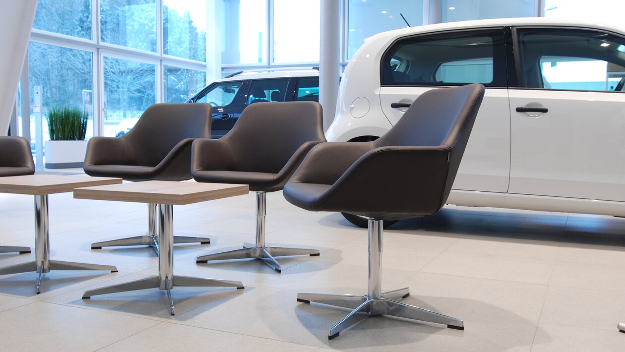 Three brown shell chairs in front of cars.