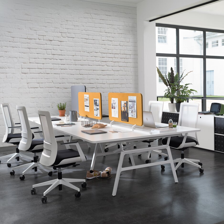 Workbench in a small office with white swivel chairs.