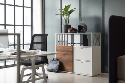 White cabinet system behind a white desk with a black swivel chair.