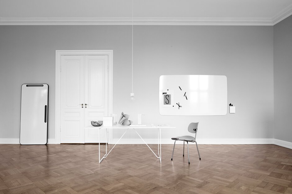 Raum mit zwei Whiteboards, einem Tisch und einem Stuhl. 