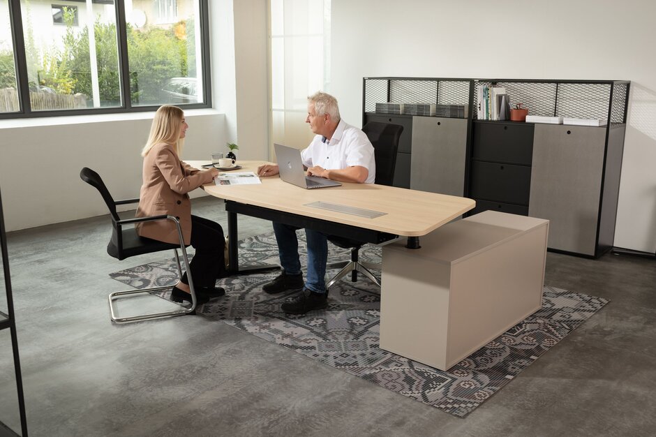 Consultingtisch mit Holzplatte, schwarzem Gestell und in Kombination mit braunem Schrank
