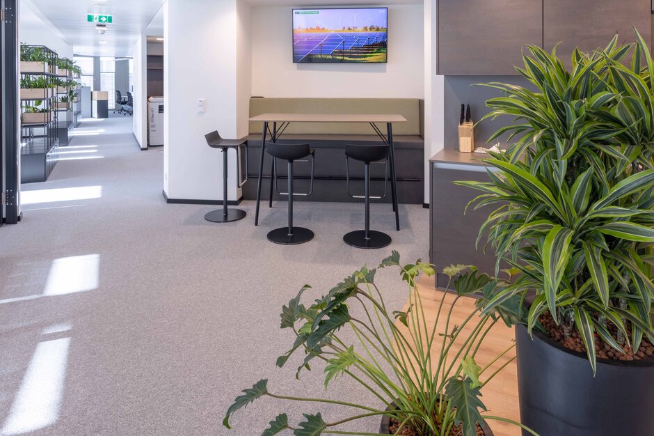 Clean Capital Energy | © Martin Zorn Photography Hoge tafel met bank en krukken, kitchette en planten | © Martin Zorn Photography