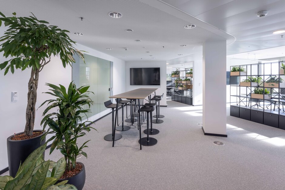 Clean Capital Energy | © Martin Zorn Photography Table de bar avec tabourets noirs et plantes au premier plan | © Martin Zorn Photography