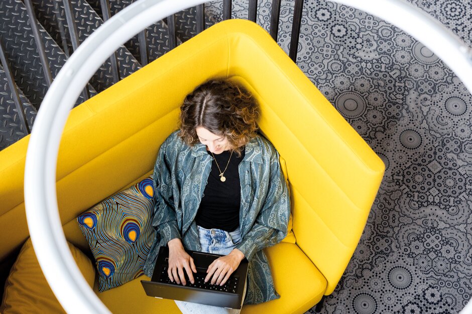 Person is working in a yellow lounge seating.