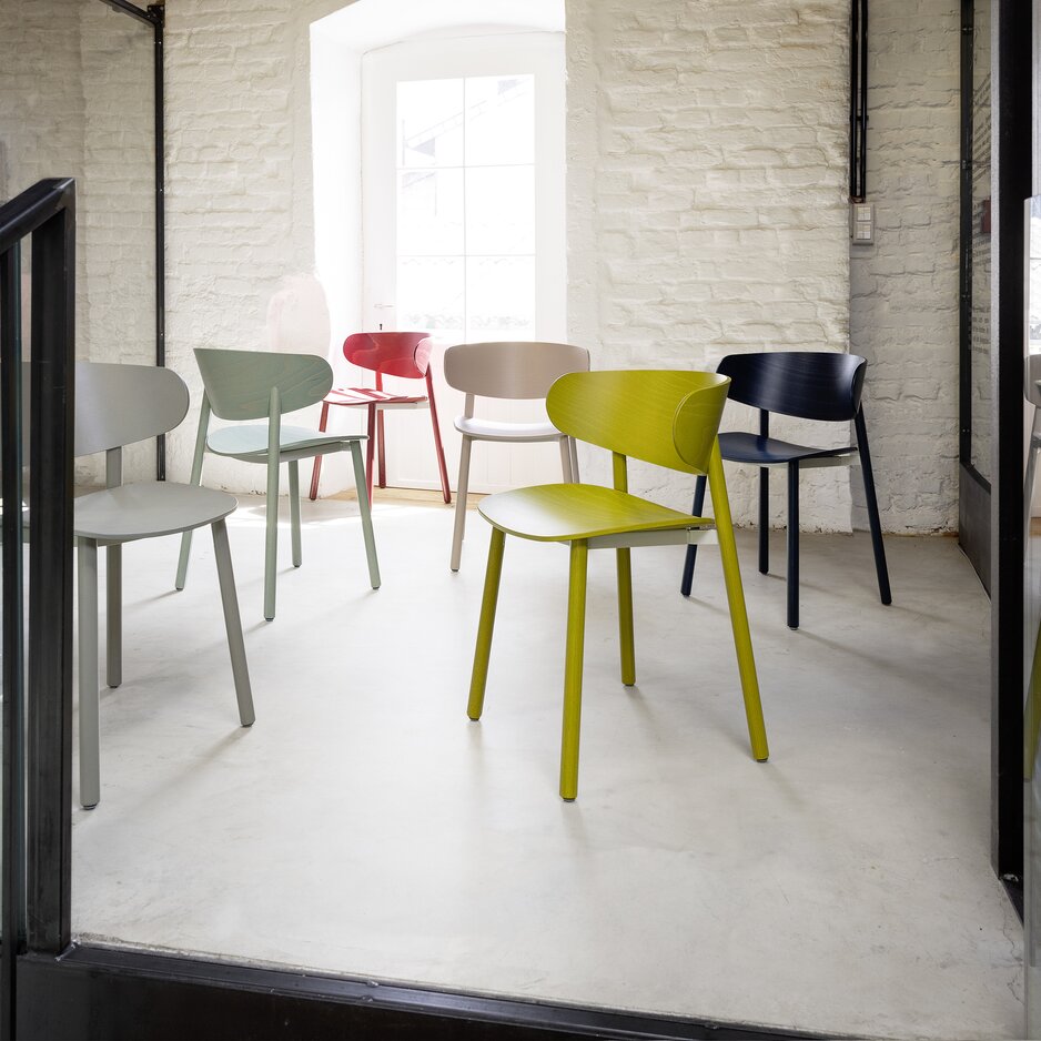Colourful wooden chairs in front of a white wall.