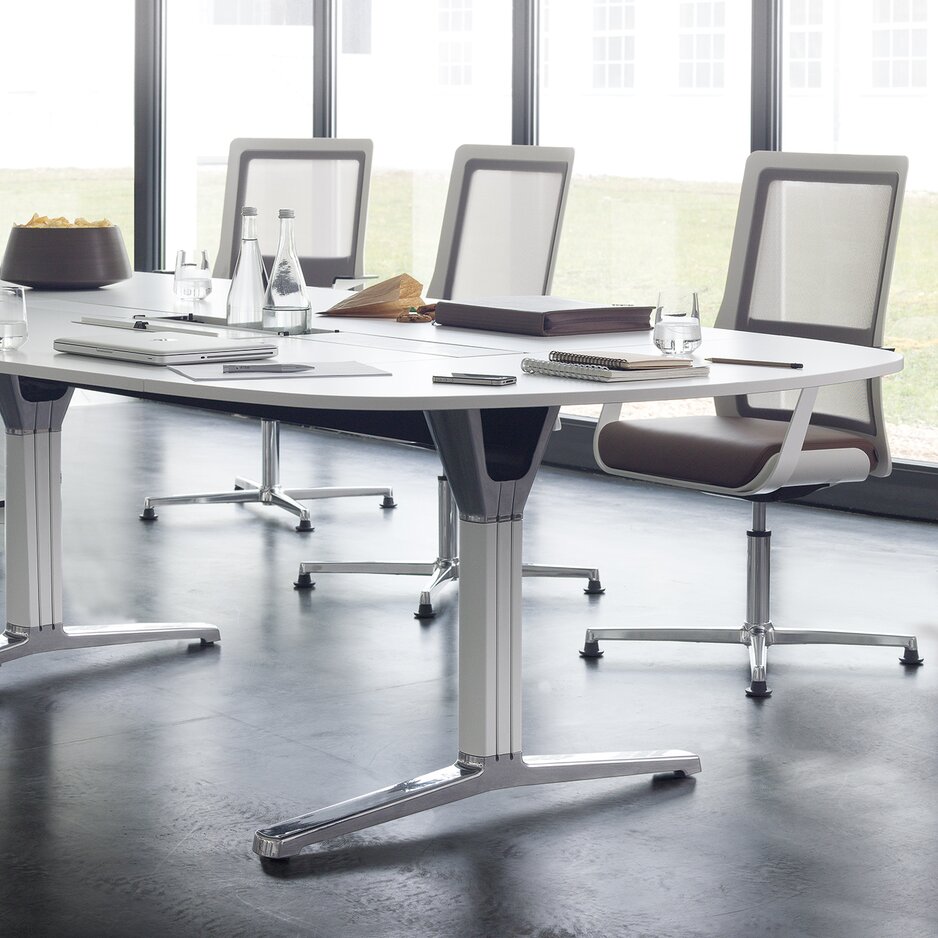 uitsnede van een vergaderruimte met een lange witte tafel en witte conferentiestoelen