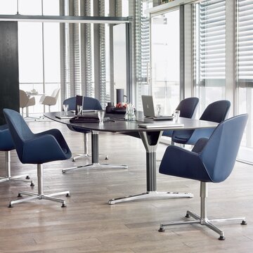 Konferenztisch mit blauen Konferenzstühlen.