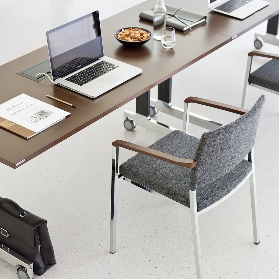 Gray chair with armrest at a conference table.