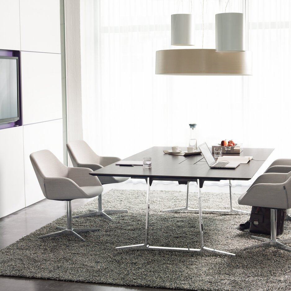 Conference table with white chairs and a gray carpet.