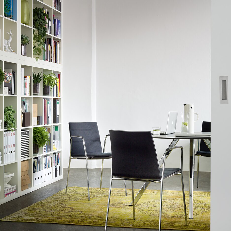 chaises rembourrées noires autour d'une table ronde et une librairie