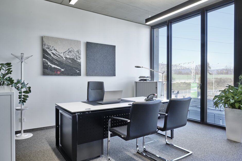 Office with black desk and black chairs.