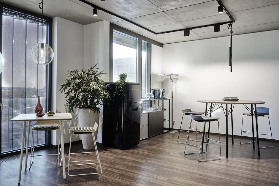 High tables, barstools and a black fridge.