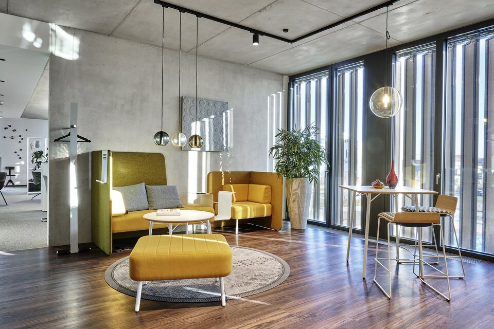 Yellow lounge seating and a high table with two barstools. 