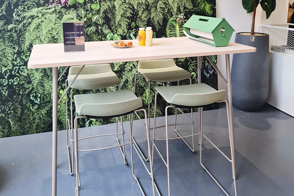 High table with green barstools in front of a plant image.