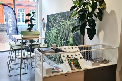 Clerkenwell Design Week White cabinet and a high table with four green barstools.