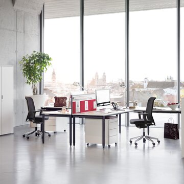 Two office desk, swivel chairs and cabinets in a glazed office.