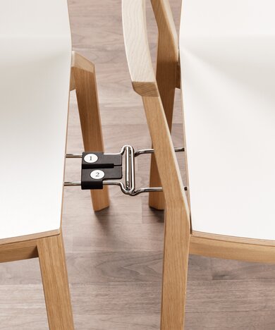 Element waarmee twee stoelen met elkaar verbonden worden zodat stoelen in een rij kunnen worden opgesteld