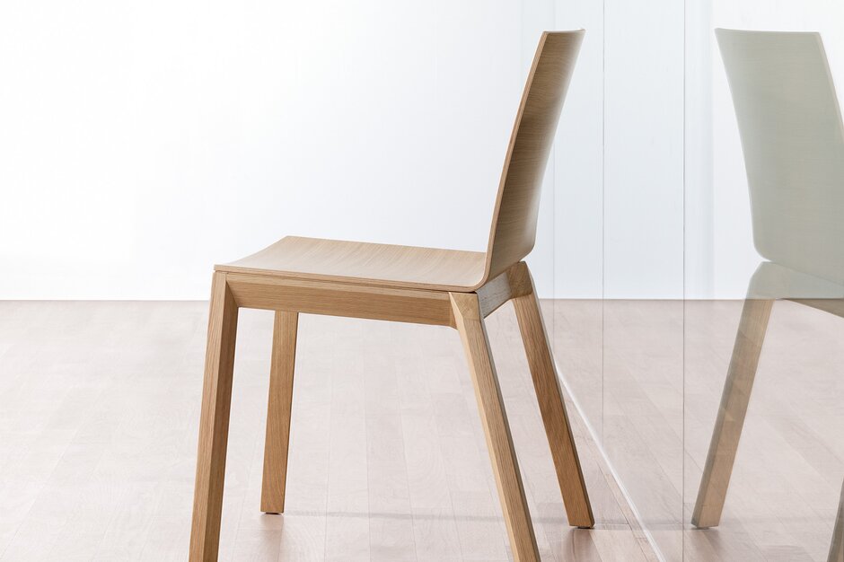 Vue latérale d'une chaise empilable en bois sans accoudoirs en chêne teinté clair avec vue en miroir
